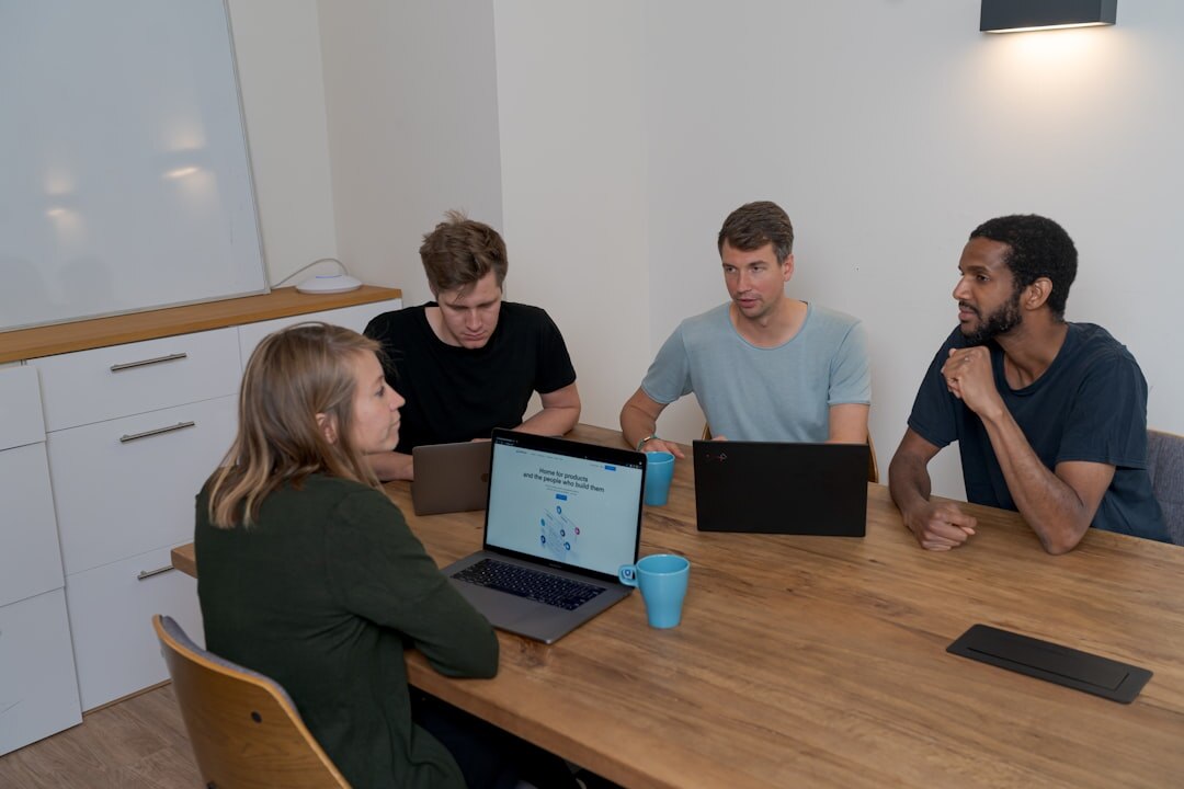 Diverse media production team collaborating around a table with laptops and tablets